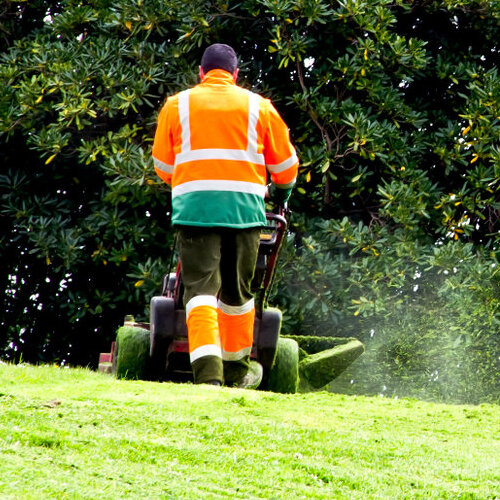 Worker mowing a large lawn.